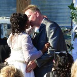 Bride and groom kissing at wedding ceremony.