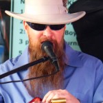 A man in a hat plays a guitar on stage.