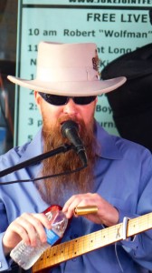 A man in a hat plays a guitar on stage.