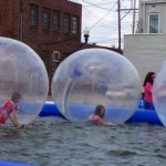 People in inflatable bubble balls in a pool.