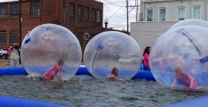 People in inflatable bubble balls in a pool.