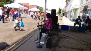 A woman plays guitar with a microphone in front of a crowd.