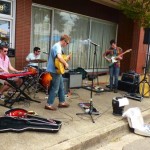 Three men play music outside a storefront.