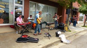 Three men play music outside a storefront.