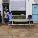 Three women sitting at a table outside a cafe.