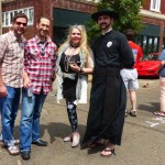 Group of friends pose in front of red car.