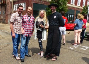 Group of friends pose in front of red car.