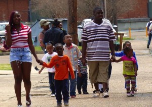 Group of people walking, including children.