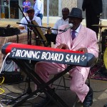 Man in pink suit plays keyboard labeled "Ironing Board Sam"