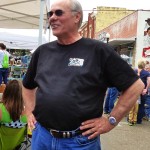 Man in black shirt with sunglasses, smiling.