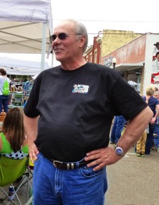 Man in black shirt with sunglasses, smiling.