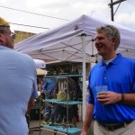 Two men talking under a white canopy tent.