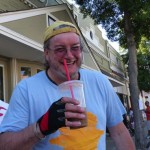 Man in blue shirt holding iced coffee.