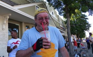 Man in blue shirt holding iced coffee.