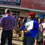 Man in blue shirt holding records in front of music store.