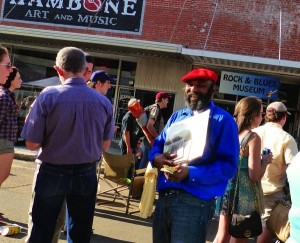 Man in blue shirt holding records in front of music store.