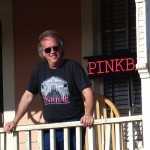 Man with sunglasses standing on a porch.