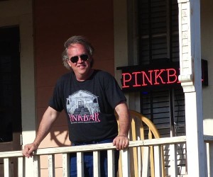 Man with sunglasses standing on a porch.