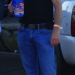 Man in black shirt and jeans holding a cup.