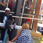 Man playing keyboard with woman in background.