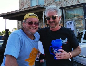 Two men smiling, one holding a cup.