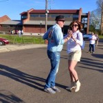 A couple dances in a parking lot.