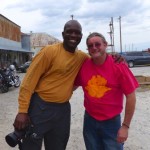 Two men smiling, one in a yellow shirt.