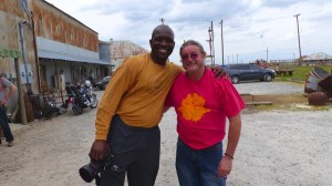 Two men smiling, one in a yellow shirt.