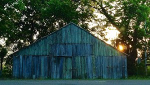 A weathered wooden barn with green siding.