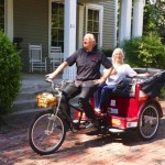 Couple riding a red bike with a basket.