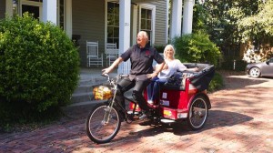 Couple riding a red bike with a basket.