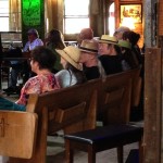 Group of people seated on a wooden bench.