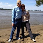 A couple smiles on a sandy beach.