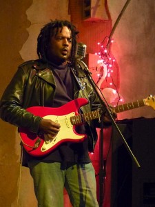 Man playing red electric guitar on stage.