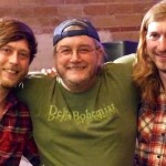 Three friends smiling, one in a green shirt.