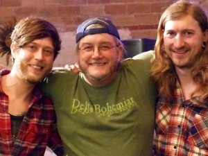 Three friends smiling, one in a green shirt.