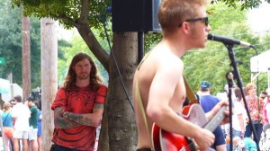 A man playing a guitar at an outdoor event.