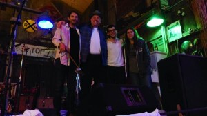 Four men and a woman stand in a music venue.