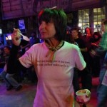 Woman smiling in a bar with a drink in her hand.