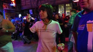 Woman smiling in a bar with a drink in her hand.