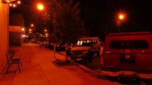 Red pickup truck parked on a street at night.