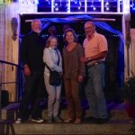 Four people stand on steps outside a building.