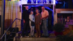 Four people stand on steps outside a building.