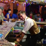 Group of people at a bar with drinks and food.