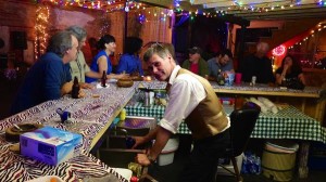 Group of people at a bar with drinks and food.