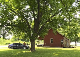 Car parked in front of a red house.