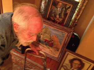 A man looks at framed paintings in a room.