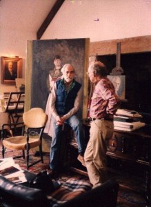 Two men talking in a room with paintings.