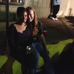 A couple holding a beer outdoors at night.