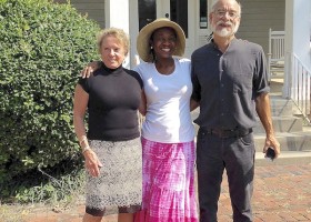 Three people standing in front of a house.